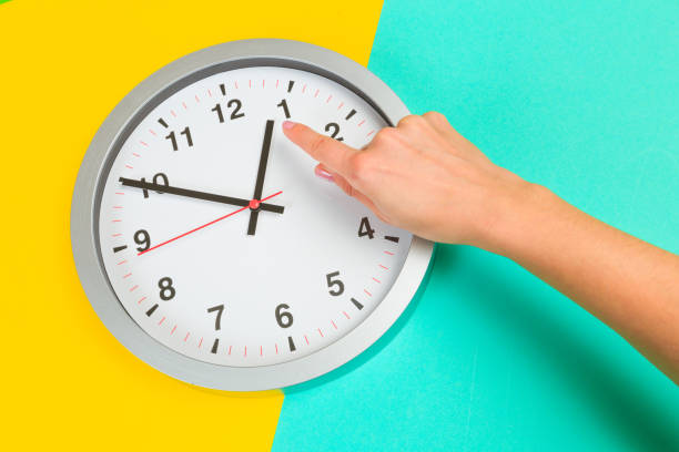 istock Beautiful young woman's hands with clock  on pastel  background - Image 1214207034