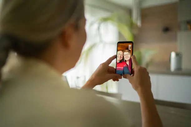 Photo of smiling senior adult parents talking with daughter over mobile phone video call