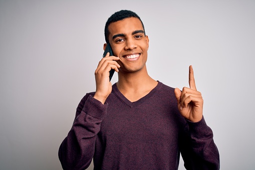 Young handsome african american man having conversation talking on the smartphone surprised with an idea or question pointing finger with happy face, number one