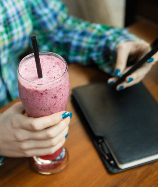 istock Girl holding milkshake with mobile phone 1214210322