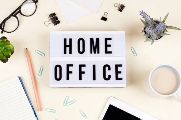 istock lightbox with text HOME OFFICE with notebook pencil glasses flowers and tea. 1214211931