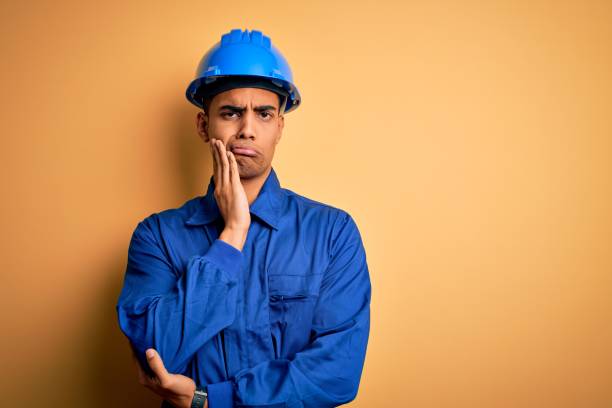 istock Young handsome african american worker man wearing blue uniform and security helmet thinking looking tired and bored with depression problems with crossed arms. 1214211980