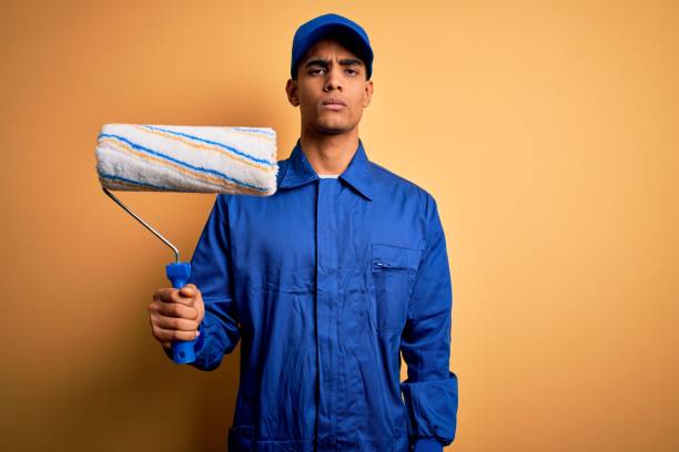 istock Young handsome african american painter man wearing uniform using painting roller with a confident expression on smart face thinking serious 1214212115