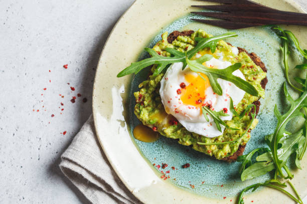 Avocado and poached egg toast on rye bread, top view. stock photo