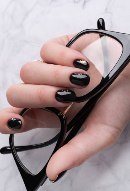istock Beautiful womans hand with elegant manicure. Minimal black nail design. 1214212697