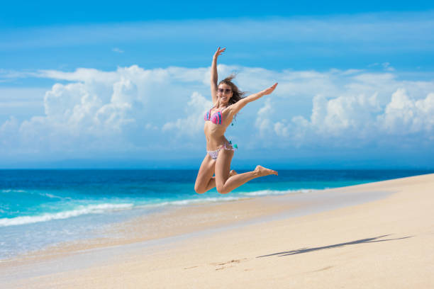 Beautiful woman in bikini jumping on beach