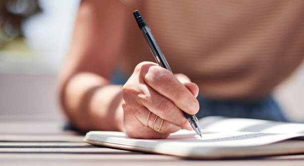 Retirement has given her the time to work on her book Cropped shot of an unrecognizable senior woman writing in her book outside on the balcony at home handwriting stock pictures, royalty-free photos & images