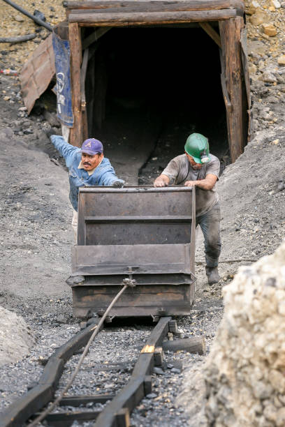 un par de mineros empujan un carro de carbón de una mina en el norte de méxico - pushing over burdened rock men fotografías e imágenes de stock