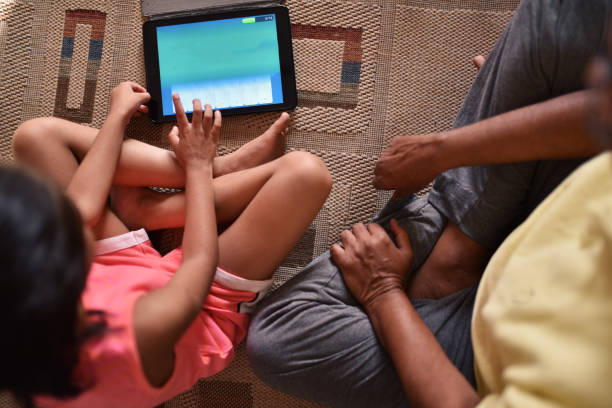 istock Girl using digital tablet with grandfather 1214219393