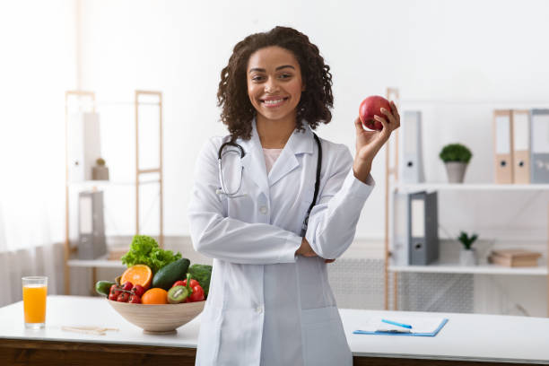 istock Pretty black lady dietologist holding apple in her hand 1214221007