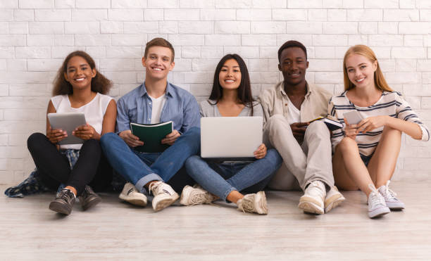 istock Smiling group of international students studying over white brick wall 1214222223