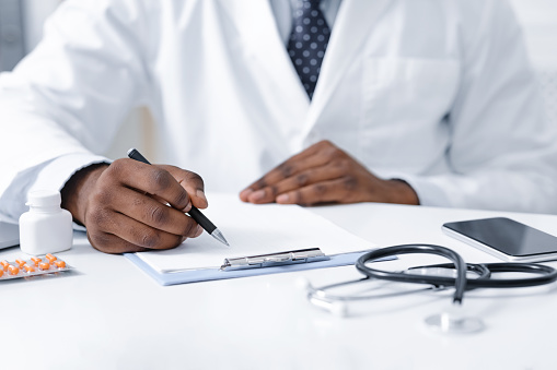 Close up of black doctor prescribing pills to patient, clinic interior