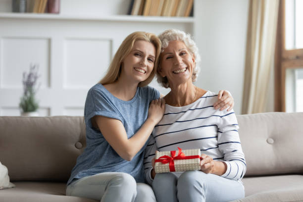 istock Grownup daughter greeting mom presenting gift package 1214223625