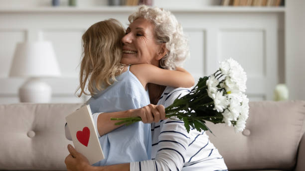 amorevole bambina che saluta la nonna con anniversario - grandmother giving gift child foto e immagini stock
