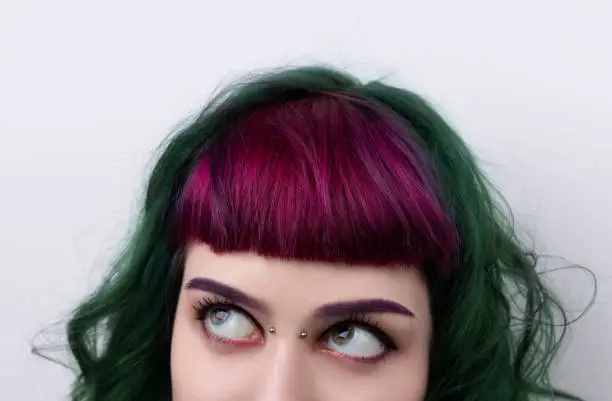 Beautiful woman with purple green professional colored hair. Bright eyes and lips makeup. Fashion girl with short hair and piercing.