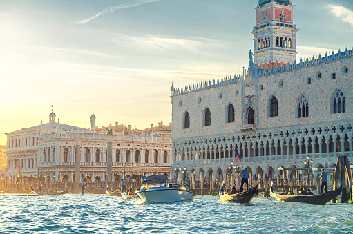 Venice cityscape with gondolas and yacht boats on water of San Marco basin, Riva degli Schiavoni waterfront promenade, Doge's Palace Palazzo Ducale Venetian Gothic style building, Veneto Region, Italy