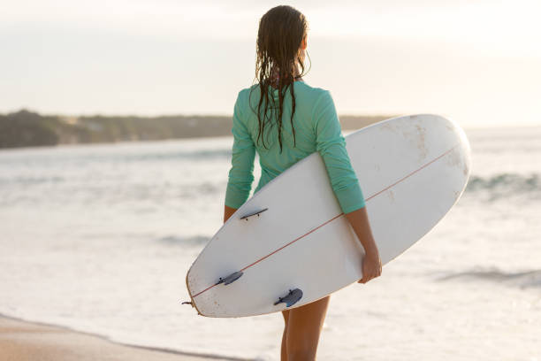 istock Surfer girl standing with surfboard on the beach 1214224890