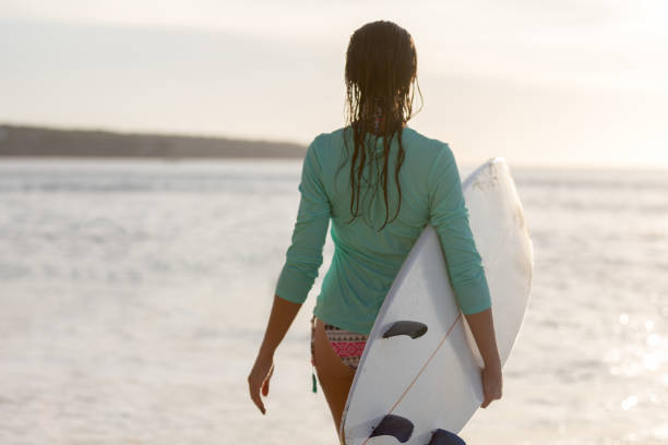 istock Surfer girl standing with surfboard on the beach 1214225845