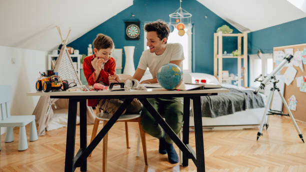 Homeschooling Photo of a young boy being homeschooled by his father in his bedroom curfew stock pictures, royalty-free photos & images