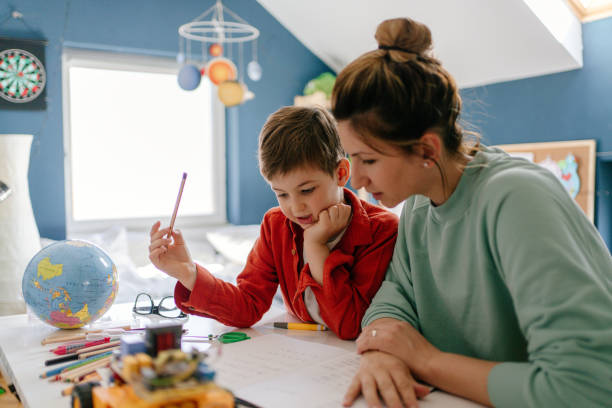 Homeschooling Photo of a young boy being homeschooled by his mother in his bedroom one kid only stock pictures, royalty-free photos & images