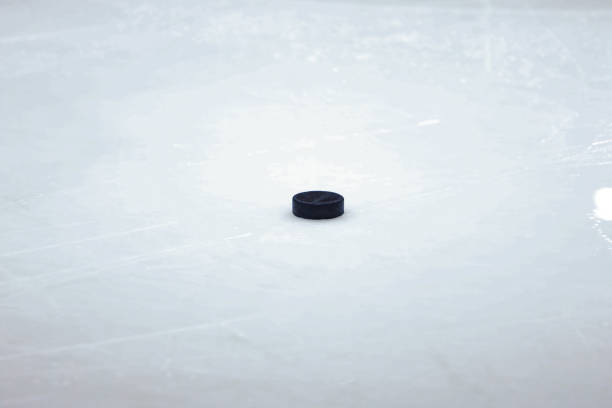 istock Black old ice hockey puck on ice rink. 1214226753