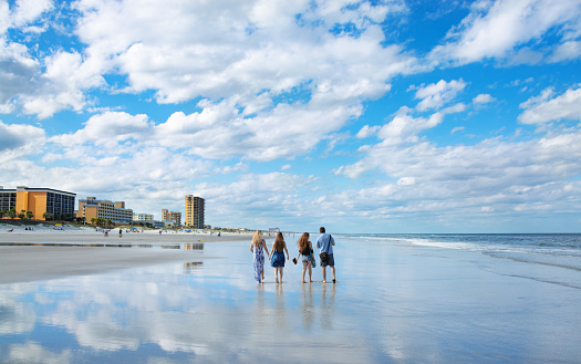 People walking on the beach. Family enjoying time together on beautiful Florida beach. Buildings and hotels in the background.Jacksonville, Florida, USA.