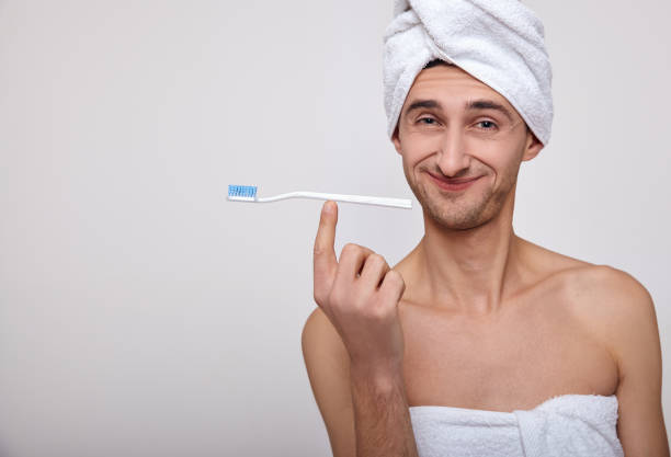 istock A joyful man in a towel on his head brushes his teeth. 1214228936