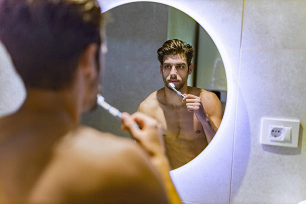 istock Reflection in a mirror of a man brushing his teeth in the morning. 1214232799