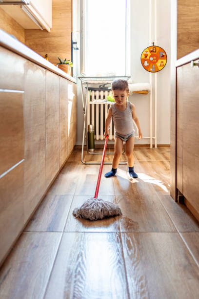 Child washing floor with mop Cute brown hair boy helping with housekeeping in classical kitchen with wooden cabinetry cleaning tiles floor with wet flat mop sweeping photos stock pictures, royalty-free photos & images