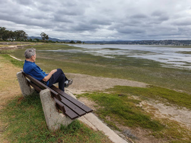 A solitary man sitting on a bench beside a lagoon.