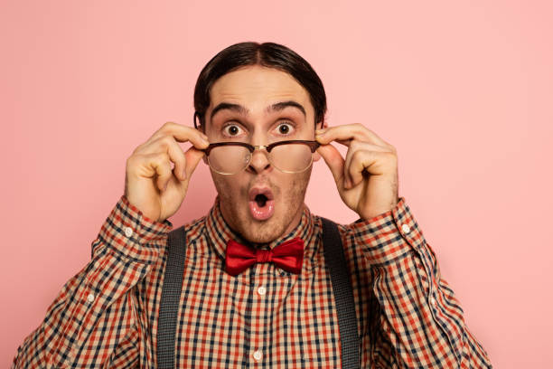 istock shocked male nerd holding eyeglasses, Isolated on pink 1214238845