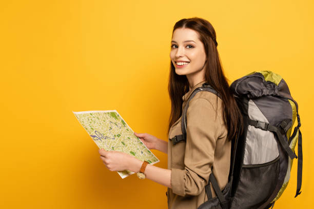 istock smiling female tourist with backpack holding map on yellow 1214239299