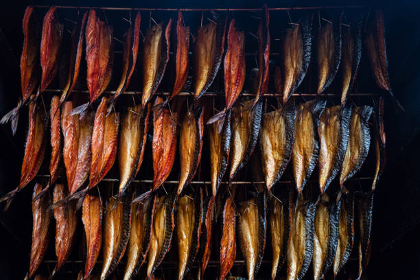filetti di pesce fumanti appesi fianco a fianco in un fumatore. pezzi di sgombro affumicati freddi in vendita nel mercato del pesce - market fish mackerel saltwater fish foto e immagini stock