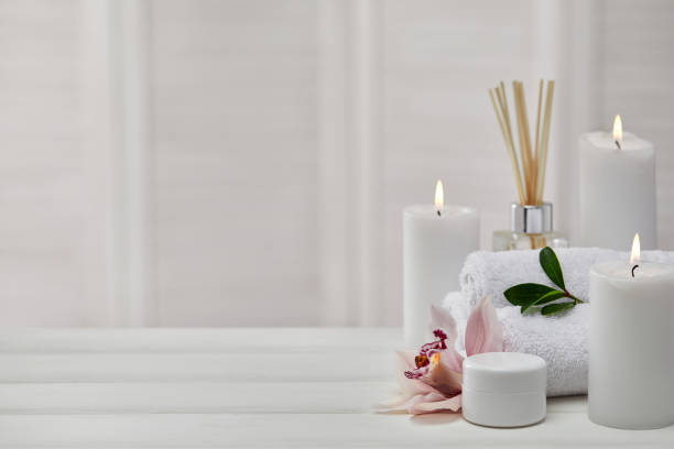 Spa treatments on white wooden table Spa products with aromatic candles, orchid flower and towel on white wooden table. Beauty spa treatment and relax concept. copy space spa room stock pictures, royalty-free photos & images