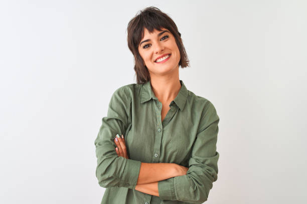 молодая красивая женщина в зеленой повседневной рубашке, стоящей над изолированным белым фоном счастливое лицо улыбается со скрещенными р - arms crossed стоковые фото и изображения