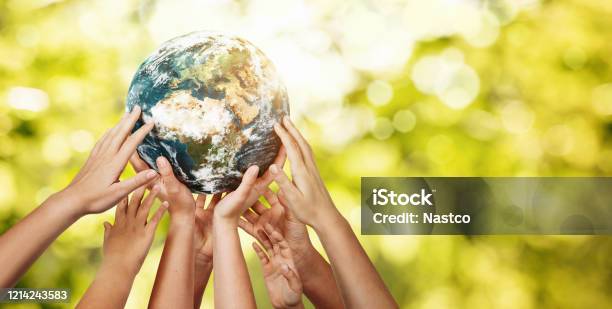Group Of Children Holding Planet Earth Over Defocused Nature Background Stock Photo - Download Image Now