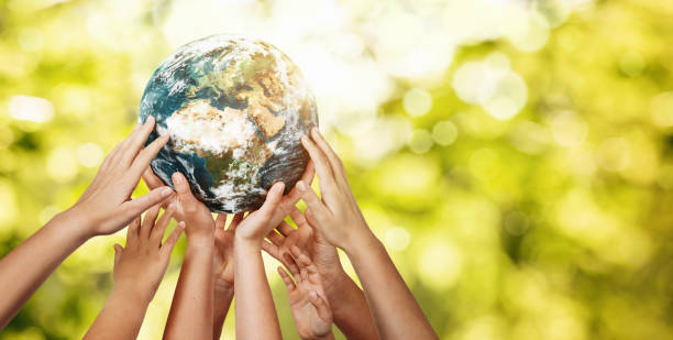 group of children holding planet earth over defocused nature background - sustainability imagens e fotografias de stock