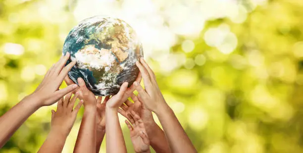 Group of children holding planet earth over defocused nature background with copy space. Element of this image furnished by NASA ( https://earthobservatory.nasa.gov/blogs/elegantfigures/2011/10/06/crafting-the-blue-marble/ )