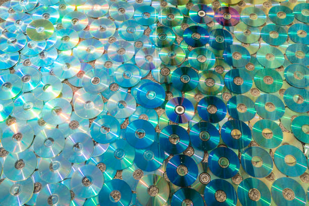 Sun reflection view, as in water,  of multicolored, old technology, waste CD/DVD as decoration for pattern, textured background.