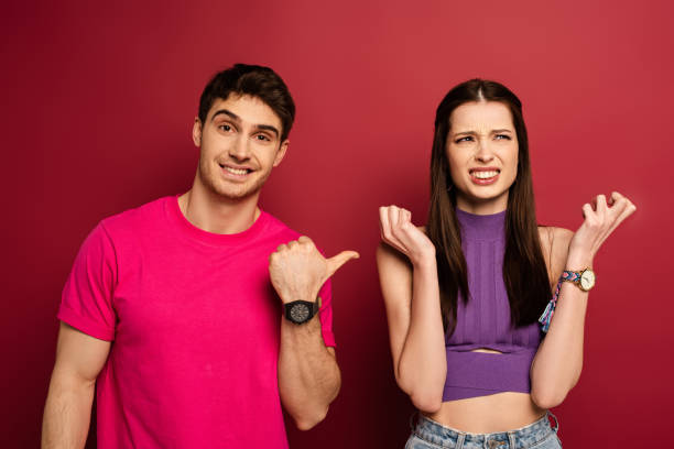 istock smiling boyfriend showing confused girlfriend on red 1214244703