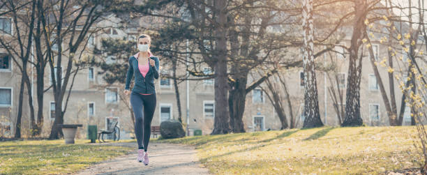 Woman jogging down a path boosting her immune system for covid-19 Woman jogging down a path boosting her immune system and fitness for covid-19 curfew stock pictures, royalty-free photos & images