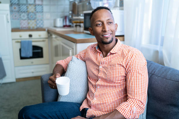 istock African man sitting at home and drinking coffee 1214249127