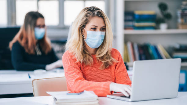 Colleagues in the office working while wearing medical face mask during COVID-19 Colleagues in the office working while wearing medical face mask during COVID-19 world health organization photos stock pictures, royalty-free photos & images