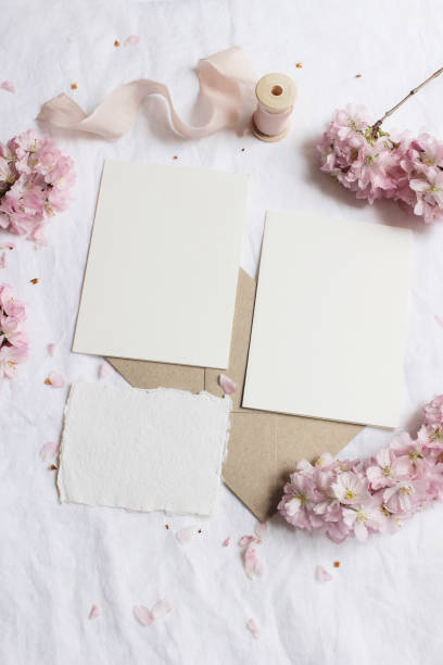 istock Wedding stationery mock-up scene. Blank greeting cards, envelope on linen tablecloth background with pink blossoming cherry tree branches and ribbon. Feminine still life composition. Flat lay,vertical 1214253618