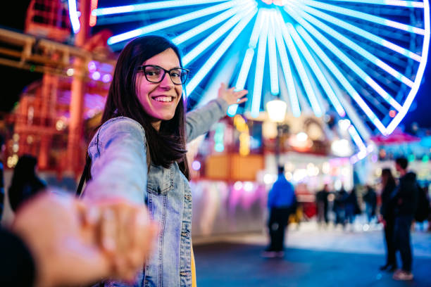 Young Caucasian pretty woman leading her man by hand to amusement park. POV concept.