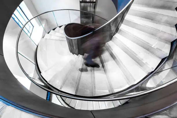 Photo of Blurred Motion of Urban Person Running down Futuristic Modern Spiral Staircase