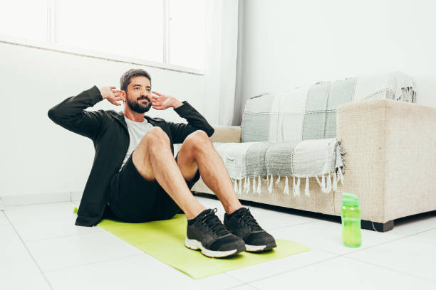 hombre haciendo ejercicio en casa haciendo sit ups - sit ups fotografías e imágenes de stock