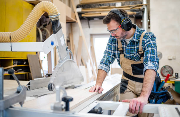 istock Carpenter using circular saw to cut a large wooden board at carpentry workshop 1214258302