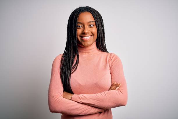 joven mujer afroamericana de pie casual y fresco sobre fondo blanco aislado cara feliz sonriendo con los brazos cruzados mirando a la cámara. persona positiva. - trenzas fotografías e imágenes de stock