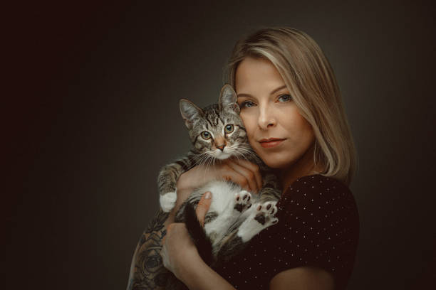 Young attractive woman holding cute kitty. Studio shot.